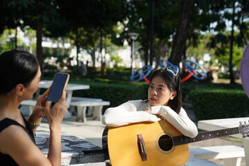 Young woman relaxing in park to do recreational activities, such as playing acoustic guitar in a park.