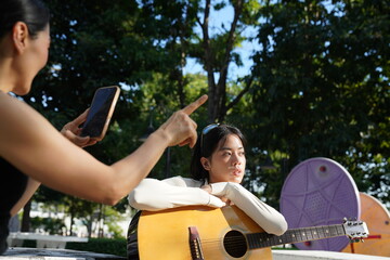 Young woman relaxing in park to do recreational activities, such as playing acoustic guitar in a park.