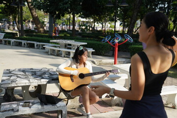 Young woman relaxing in park to do recreational activities, such as playing acoustic guitar in a park.