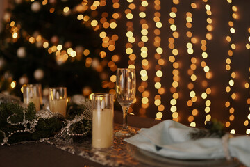 Festive holiday dinner table setting with champagne flute and glowing bokeh lights