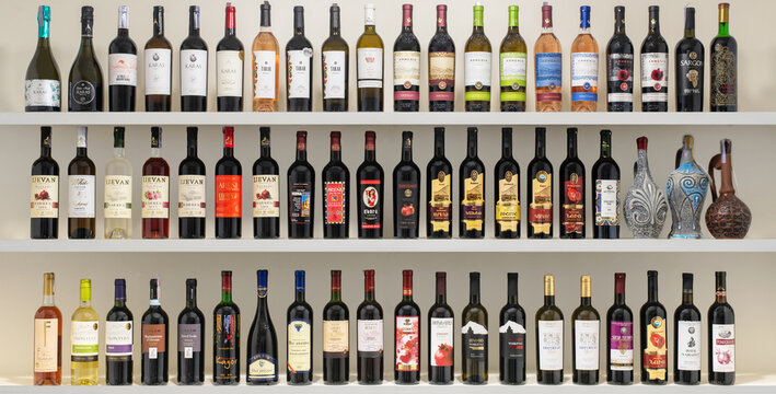 A shelf full of wine bottles with a variety of colors and labels