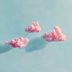 Three fluffy pink clouds drift gently across a pale blue sky with soft shadows beneath