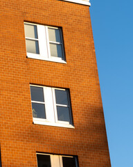 Building with orange brick facade and white windows against a clear blue sky during daytime