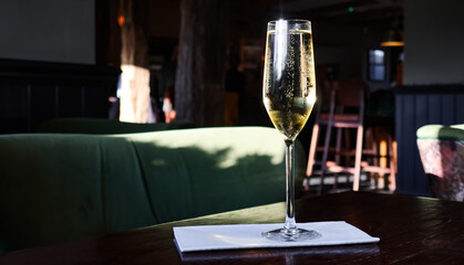 Glass of sparkling wine on a table, bubbles rising, creating a cheerful atmosphere in a restaurant setting