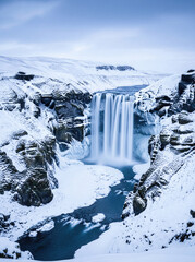Majestic waterfall in snowy winter canyon landscape
