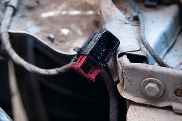 Electrician works with electric block in car. Close-up of automobile inside under raised hood. Service man hands working with cables of auto
