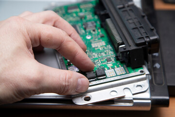 Electrician works with electric block in car. Close-up of automobile inside under raised hood. Service man hands working with cables of auto
