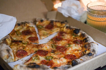 Take away pepperoni pizza on a table at home, cosy Christmas light 