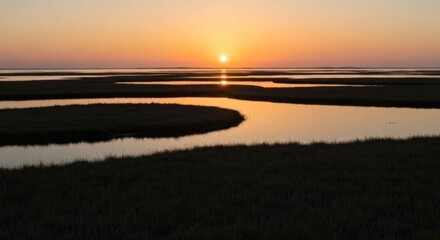 Sunset over a marshland with winding waterways reflecting the golden light