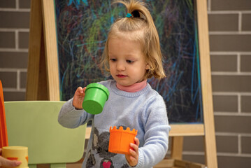 A little girl is playing with plastic cups and a chalkboard