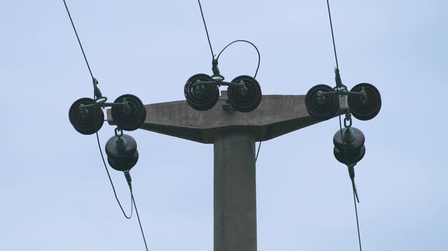 Close-up of a concrete utility pole head with ceramic insulators
