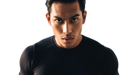 Close-up portrait of a determined young man with an intense gaze in a dark studio setting, exuding strength and focus.