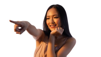 Cheerful young woman pointing while smiling in warm outdoor light, lifestyle portrait.