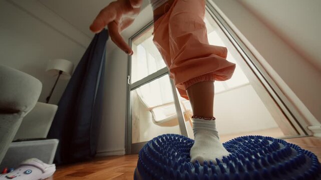Closeup of feet balancing on soft cushion near window scene