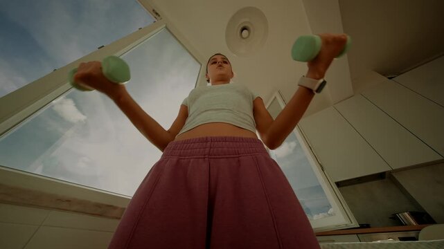 View of woman exercising with light weights through window