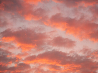 A pink sky with clouds and a sun