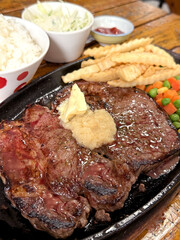 Juicy T-bone steak served with rice, french fries, and mixed vegetables