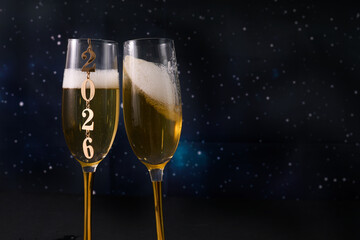 New Year Celebration. Two champagne glasses against a starry backdrop celebrating 2026.