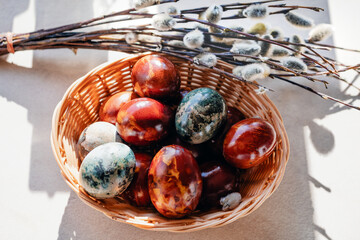Basket of naturally dyed Easter eggs with pussy willow branches on table