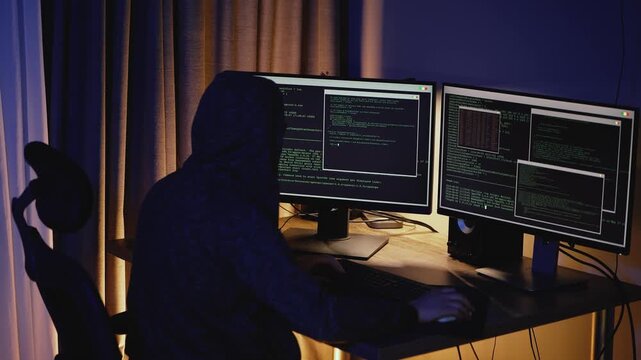 A developer works late at night in low light, focused on code and system security. Modern outsourcing workspace. Concept of cyber defense, hacking prevention, digital protection, and secure software.