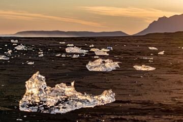 Diamond Beach panorama with scattered icebergs on black sand at sunset in Iceland