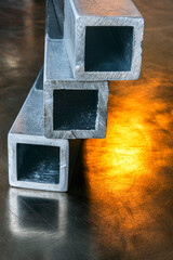 Aluminium closed profiles on an industrial steel surface reflecting light