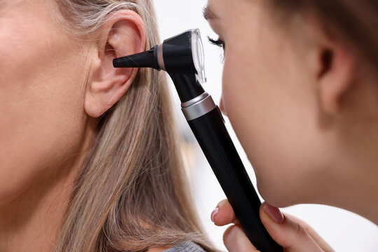 Hearing test. Doctor examining patient&rsquo;s ear with otoscope in clinic, closeup