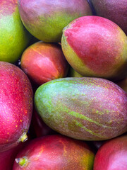 A pile of fresh ripe, juicy mangoes in the market. Food and fruit background. Top view, close-up. Fruits for sale in the supermarket.