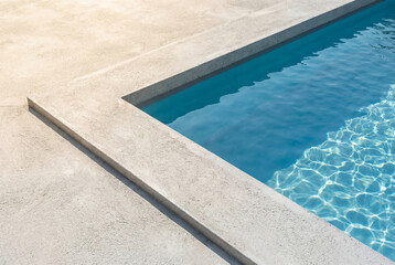 Obraz premium Minimalist swimming pool corner with clean concrete lines and blue water. Concept of luxury, summer and architectural simplicity.