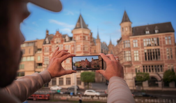 Tourist hands holding a smartphone while taking a photo of historic European city architecture. Travel photography concept, sightseeing, urban tourism, and modern technology. - Powered by Adobe