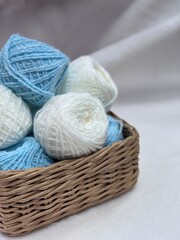 Balls of white and blue yarn, knitting and crafts, wicker basket