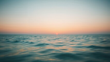 Fototapeta premium Sunset over the ocean with calm waters and a clear sky, capturing the peaceful transition between day and night.