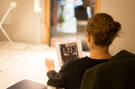 Woman reviewing blueprints on her phone while working at a desk while drinking coffee