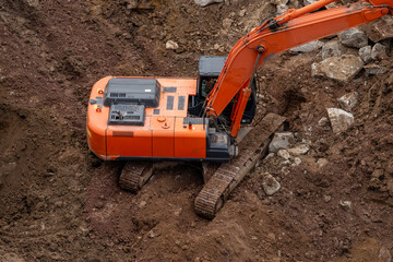 The excavator is shown in close-up from above. It is involved in the excavation of the ground for the opening of the old roadbed, which is being repaired and restored. High quality photo