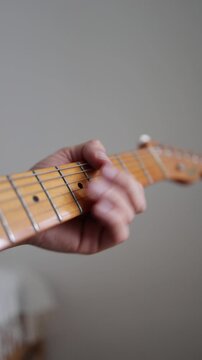 Guitarist, player and musician is playing music on the electric guitar. Fingers and hands are playing melody andmoving on the fretboard.  Minimalist vertical video with gray background. Shallow focus.