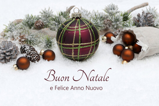 Biglietto di auguri di Natale in italiano: decorazione con palline di Natale e rami di abete nella neve. Buon Natale e felice anno nuovo.