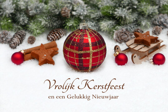 Kerstkaart met groeten in het Nederlands: Decoratie met kerstballen en dennentakken in de sneeuw. Vrolijk kerstfeest en een gelukkig nieuwjaar.