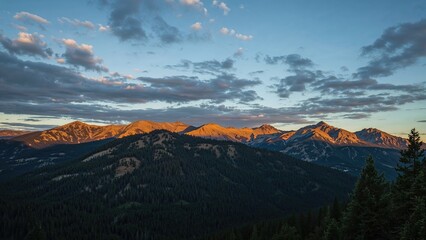 Obraz premium Mountain landscape with sunset lighting, showcasing scenic peaks and lush forests under a partly cloudy sky.
