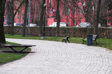 Pathway through a tranquil park with vibrant red buildings nearby