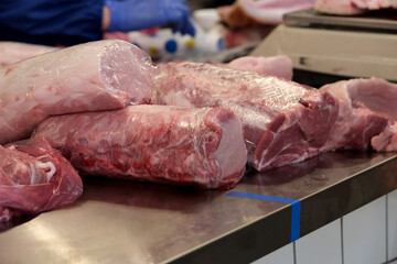 Fresh cuts of meat displayed on a stainless steel counter in a market