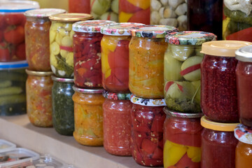 Colorful jars of preserved vegetables line a rustic wooden shelf