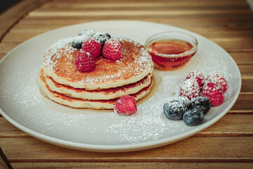 Plate with pancakes, fruits and syrup