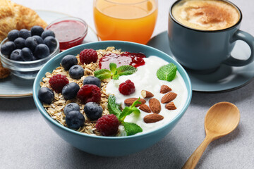 Healthy breakfast. Oatmeal with nuts, berries, yoghurt, jam, coffee and juice on grey textured table, closeup