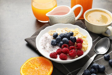 Healthy breakfast. Oatmeal with berries, yoghurt, chia seeds, coffee and orange juice on grey table, closeup. Space for text
