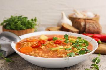 Delicious lentil soup with vegetables served on grey table, closeup