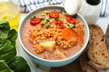 Delicious lentil soup with vegetables served on table, closeup
