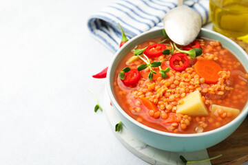 Delicious lentil soup with vegetables served on light grey table, closeup. Space for text