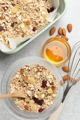 Making granola. Flat lay composition with oat flakes, dried fruits, almond nuts and honey on grey textured table