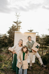 Familie steht in der Natur vor einem beigen Studiohintergrund und wirft Geschenke in die Luft