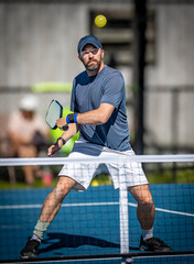 Male pickleball player about to hit backhand volley during tournament